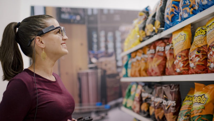 a woman wearing eye tracking glasses shopping for potato chips