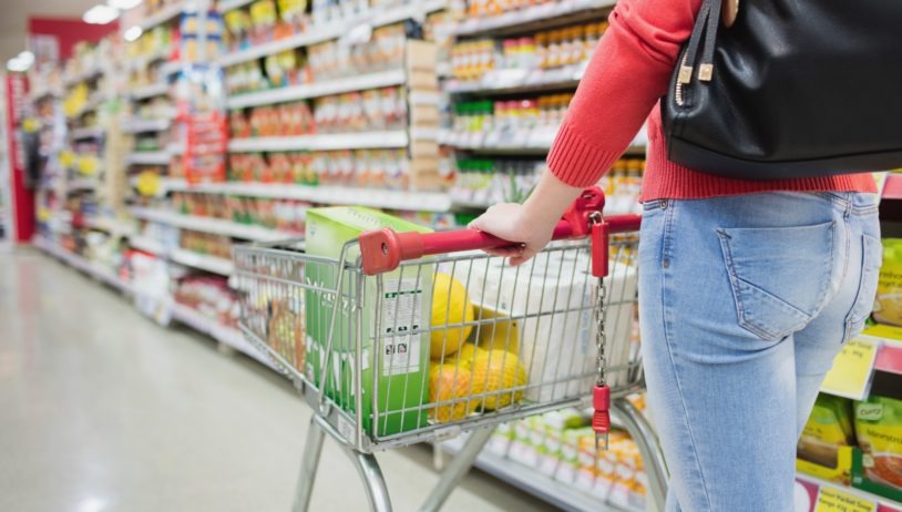Woman pushing grocery cart down aisle