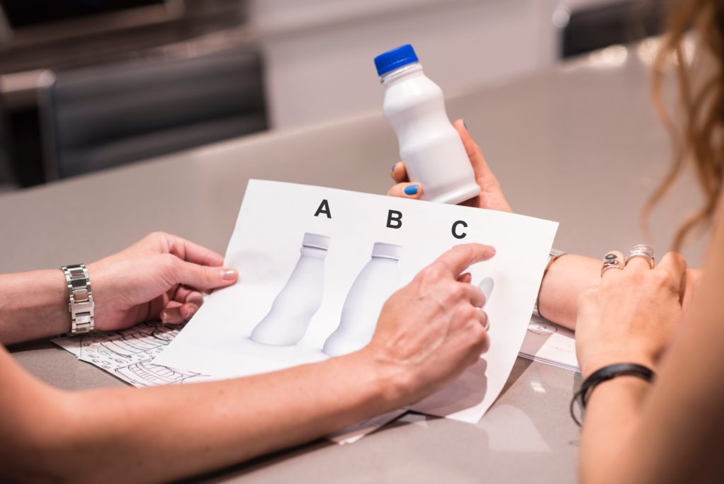 woman pointing to a sheet of paper showing three different package design prototypes