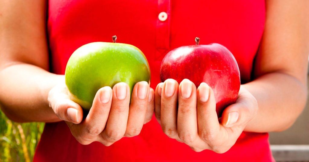 woman holding a green apple in one hand and a red apple in the other