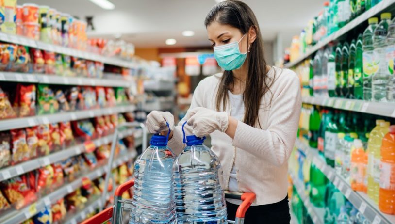 woman stocking up on water in grocery store
