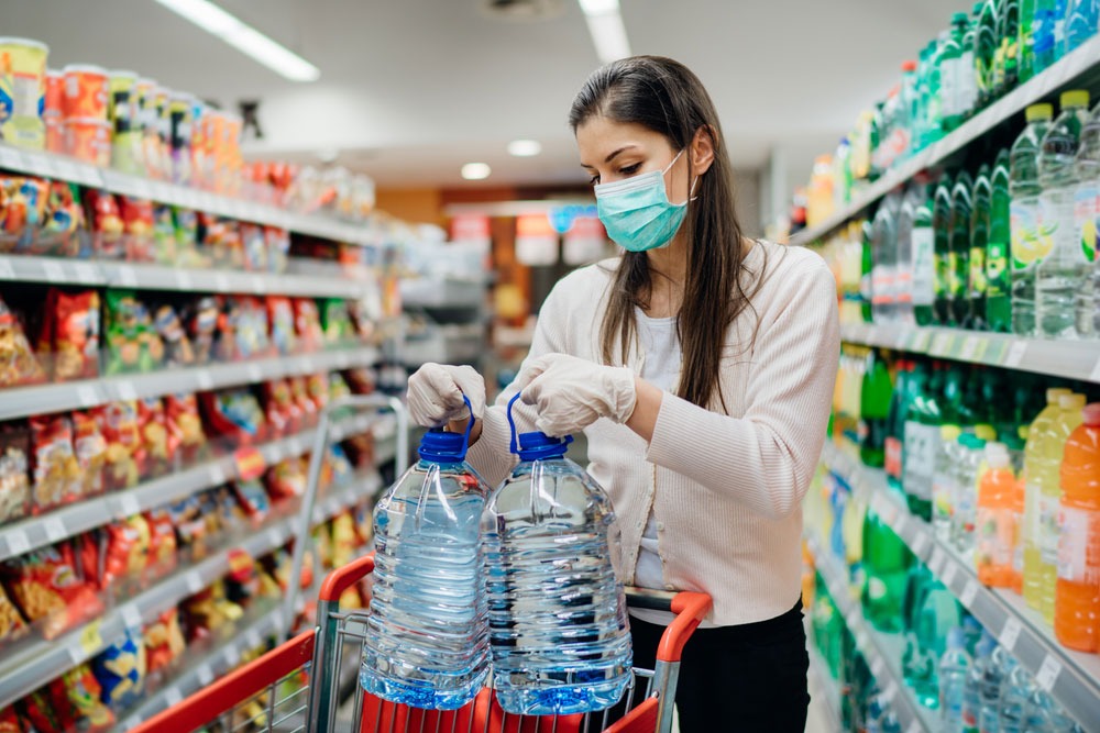 woman stocking up on water in grocery store