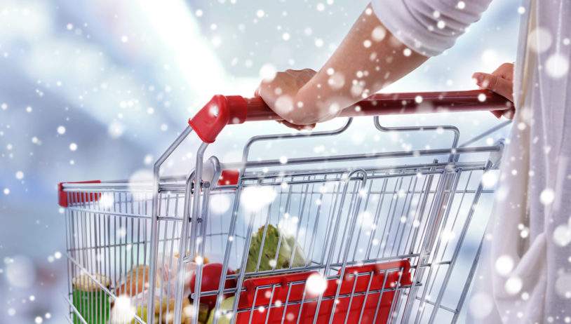 Young woman with shopping cart in store over snow effect