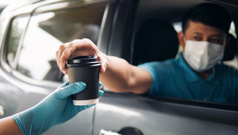 man being handed a coffee at drive-thru